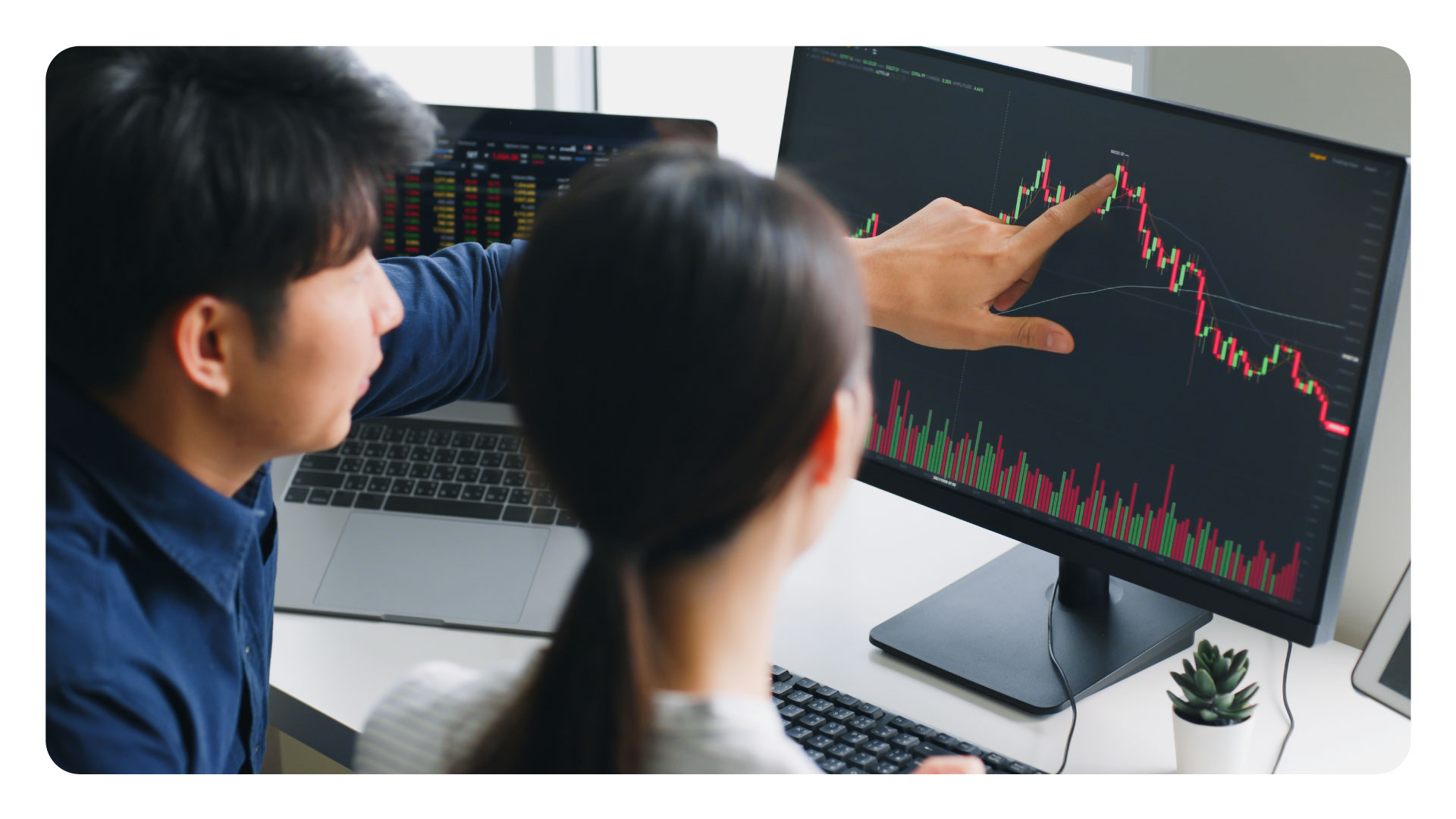 image showing two people monitoring currency movements on a computer screen